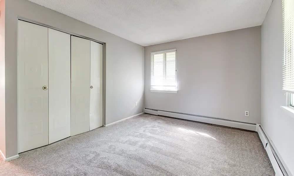 Unfurnished bedroom with two windows and double-door closet at North Dohr Apartments in Rochester, New York