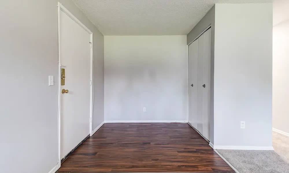 Entryway with white front door, closet, and wood laminate flooring at North Dohr Apartments in Rochester, New York