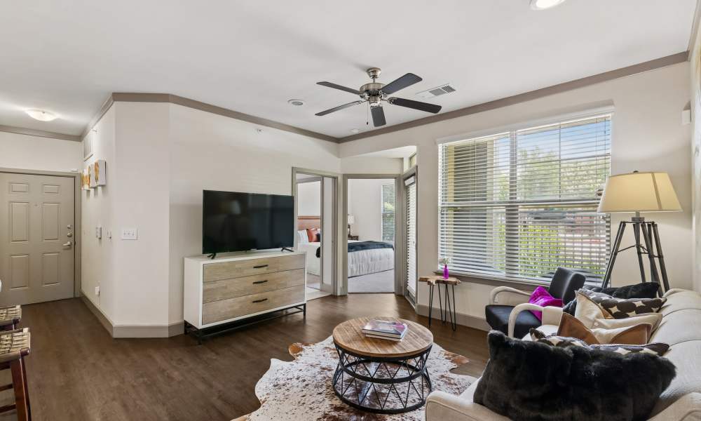 Well-decorated apartment living room with a ceiling fan, wooden flooring, and neutral colors at Plantation Park Apartments in Lake Jackson, Texas