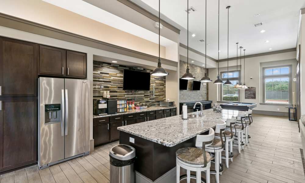 View of prep kitchen with stainless steel appliances, kitchen island with seating, and a coffee machine at Plantation Park Apartments in Lake Jackson, Texas