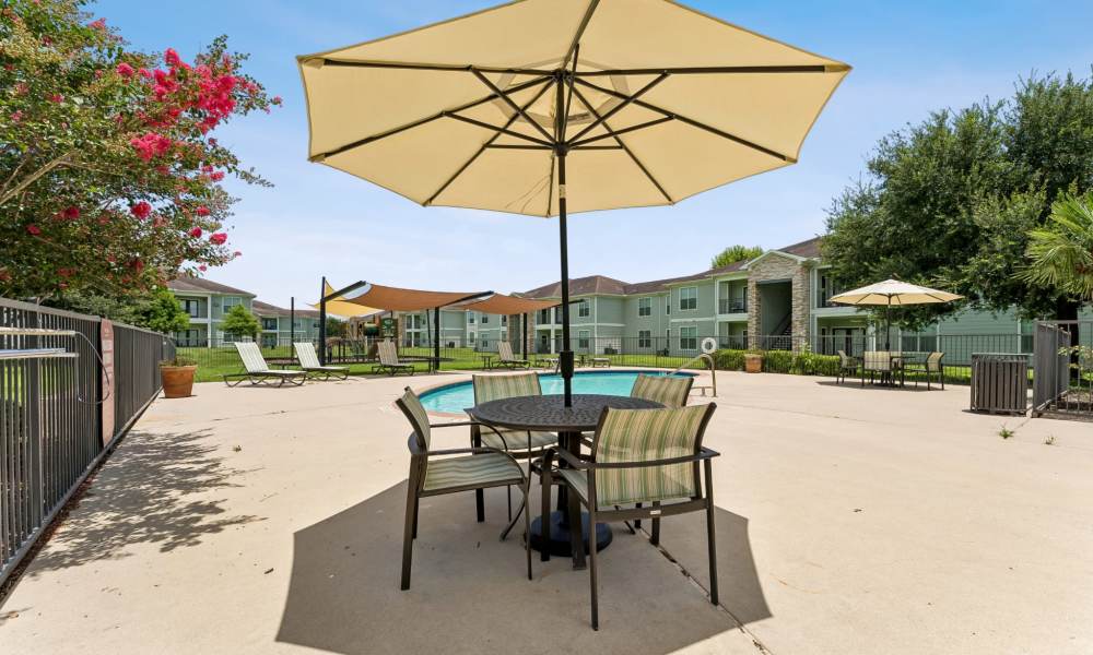 Outdoor picnic table with umbrella in the pool area at Point Royale Apartments in Victoria, Texas