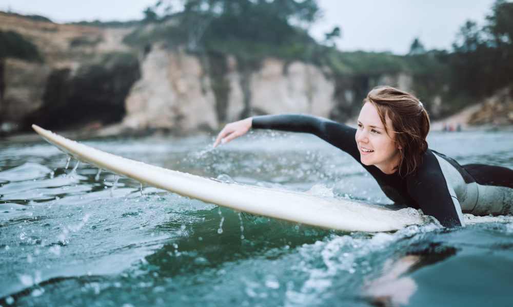 Surfer paddling on a board in ocean waves St Tropez Apartments in Marina Del Rey, California