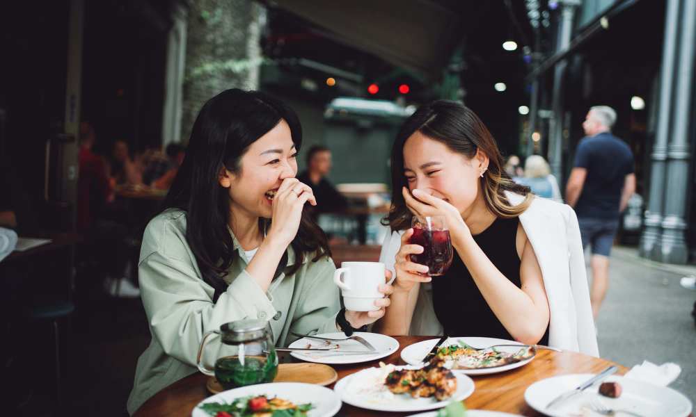 Two women laughing over brunch at a cafe near Crescent Place in Savannah, Georgia