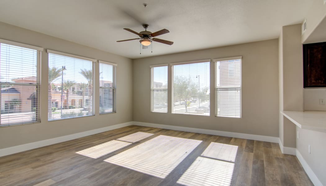 Hardwood floors and a ceiling fan in the open-concept living area of an apartment home at The Residences at Stadium Village in Surprise, Arizona