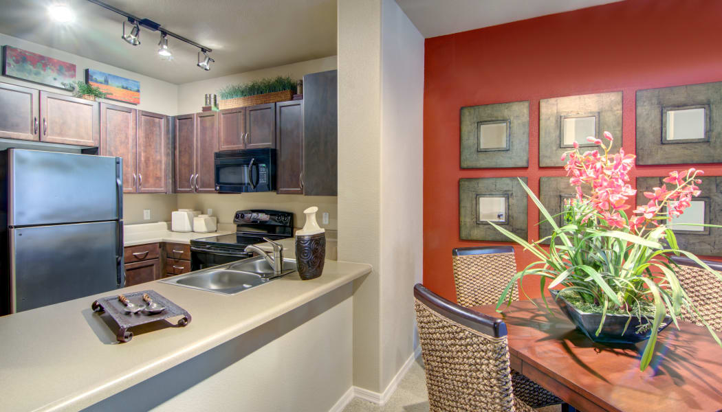 View of modern kitchen over the breakfast bar next to model home's dining area at The Residences at Stadium Village in Surprise, Arizona