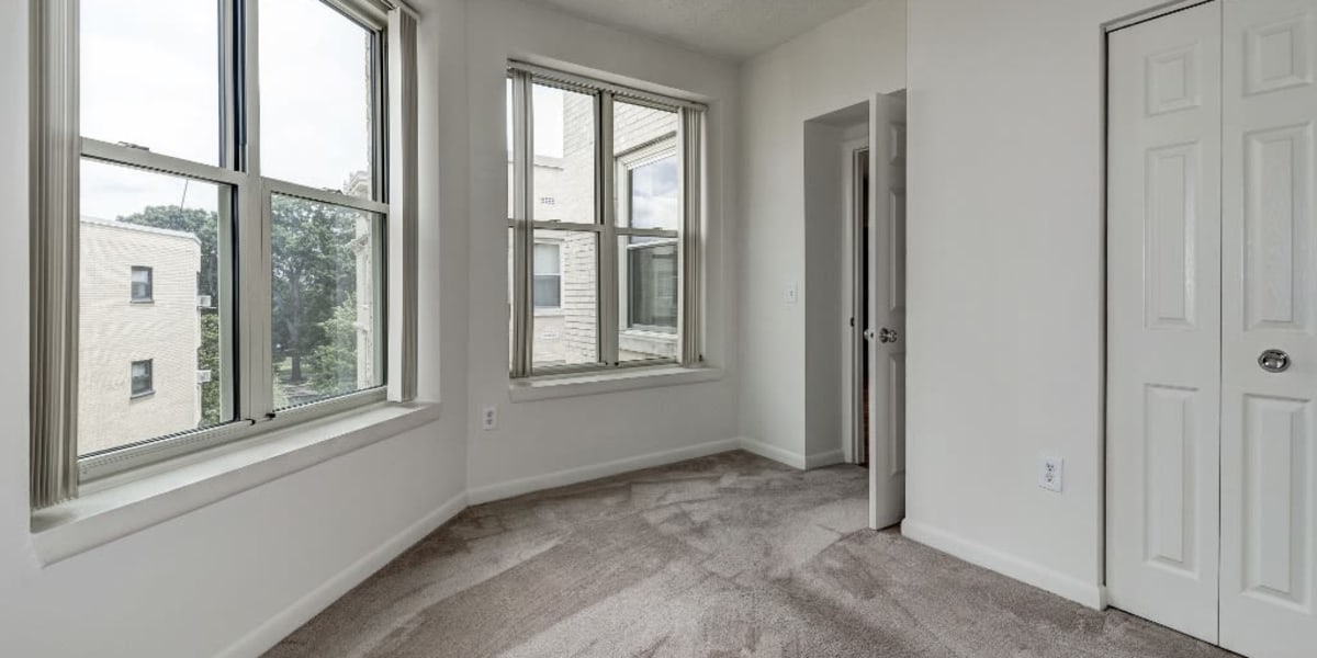 Carpeted space in the living room with two large windows that have a nice view at The Envoy Apartments in Washington, District of Columbia