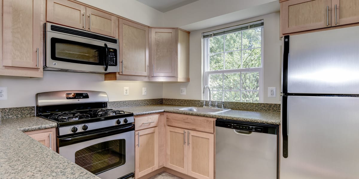 Stainless steel appliances in the kitchen with nice light wood style cabinets complimenting them at The Gardens at Del Ray in Alexandria, Virginia