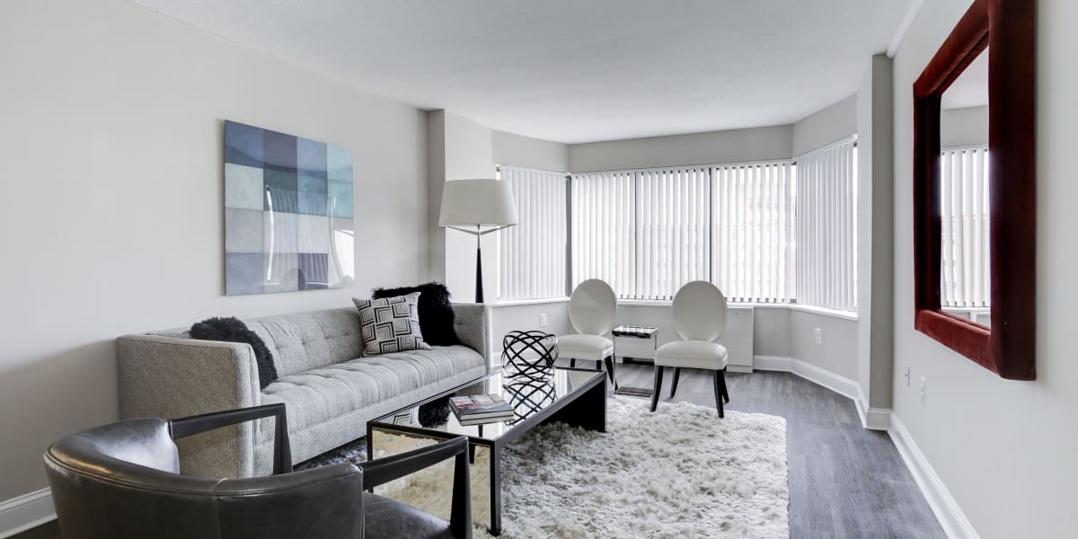 Fully furnished living room with tons of light and wood style flooring in a model home at The Cambridge Apartments in Washington, District of Columbia