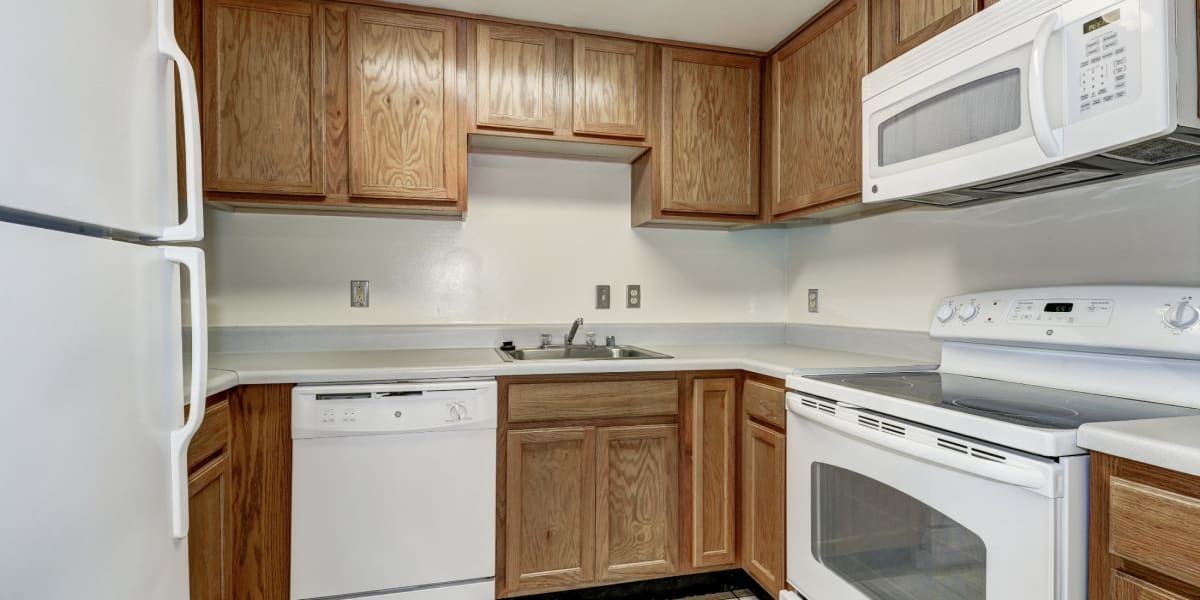 White appliances and light wood cabinets in the clean kitchen at The Delano in Adelphi, Maryland
