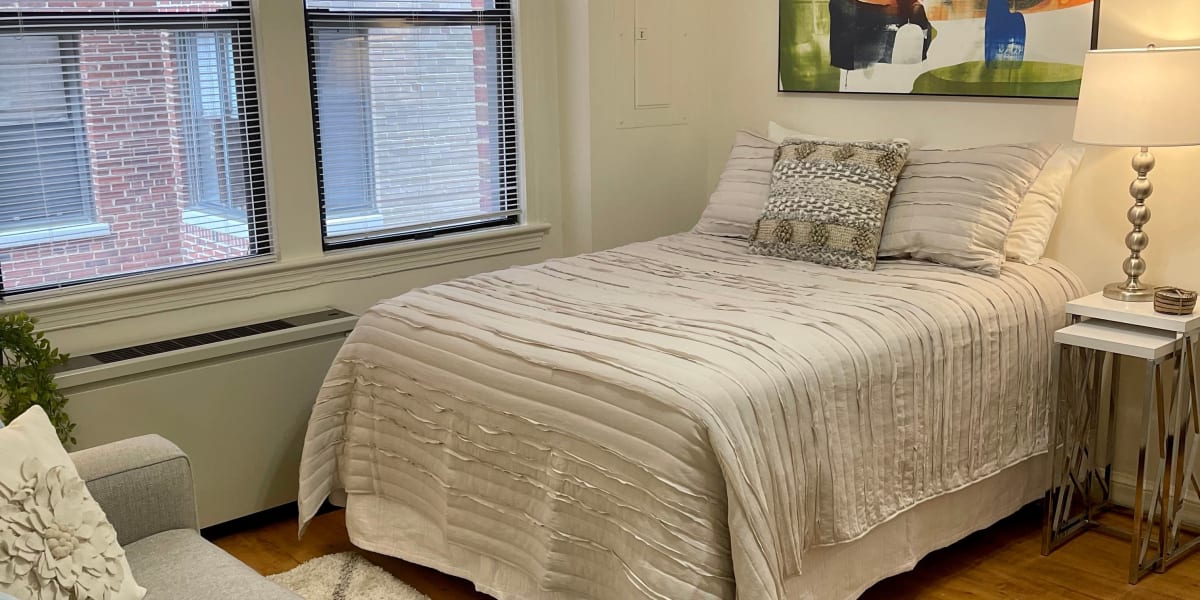 Cozy bedroom in a well lit room with hardwood style flooring at The Shoremeade Apartments in Washington, District of Columbia
