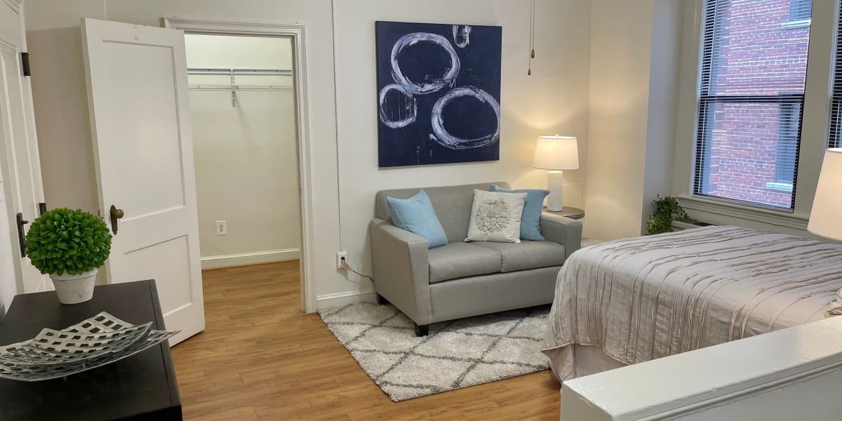 Furnished studio apartment with some cool blue artwork behind the couch at The Shoremeade Apartments in Washington, District of Columbia