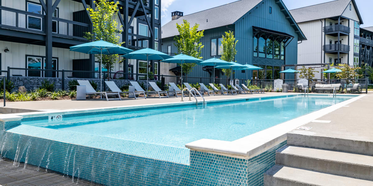 Gorgeous resort style pool with lounge chairs and umbrellas around it at Rivertop Apartments in Nashville, Tennessee