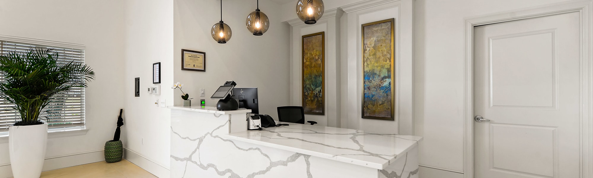 Reception area with a large marble desk and art hanging from the walls at The Blake at Biloxi in Biloxi, Mississippi