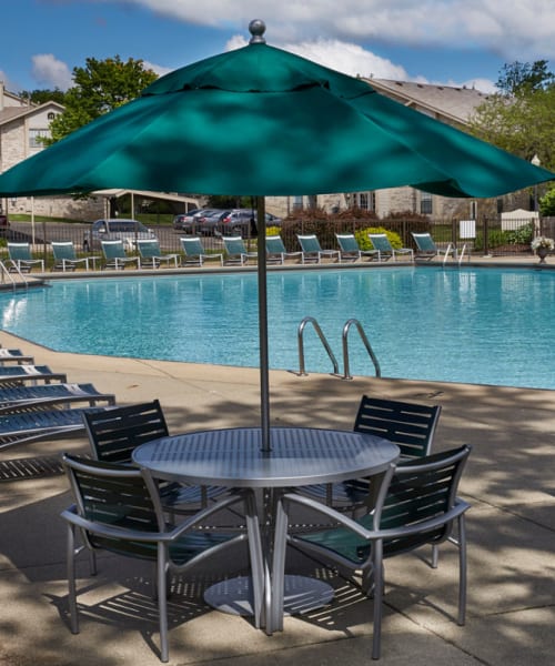 Outdoor swimming pool with shaded patio table at Muirwood in Farmington Hills, Michigan