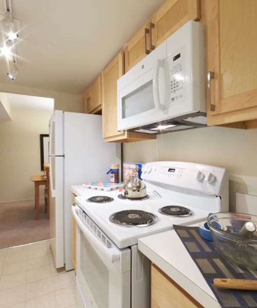 Kitchen with white appliances including built-in microwave at Kensington Manor Apartments in Farmington, Michigan