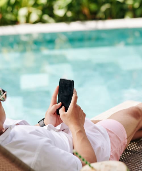 Resident checking his phone near swimming pool at The Palms, Los Angeles, California