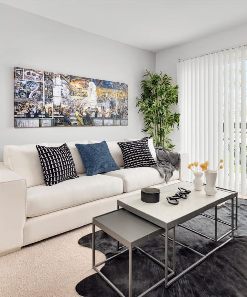 Living room with a white sofa and nesting coffee table at Fairmont Park Apartments in Farmington Hills, Michigan