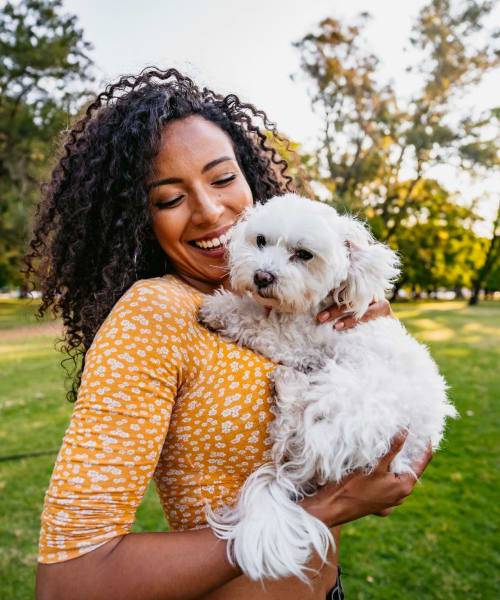 Woman holding her dog at park near Lakewood Apartments at Lake Merced in San Francisco, California