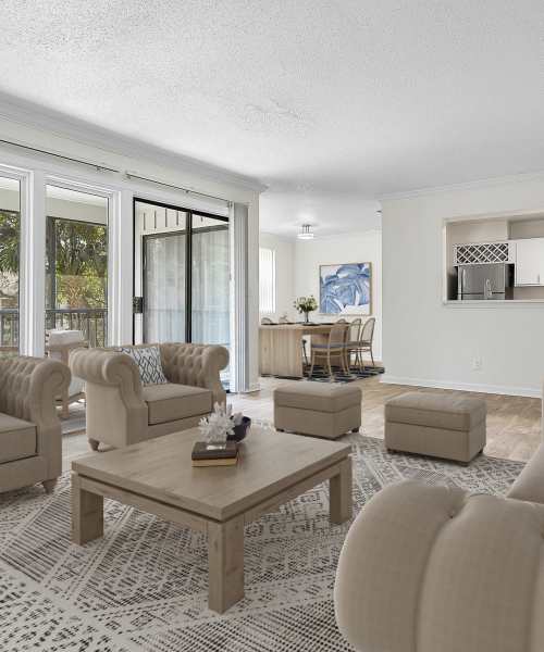 Living Room With Beige Chesterfield Sofas, Wooden Coffee Table, And Large Glass Doors at The Avenues in Jacksonville, Florida