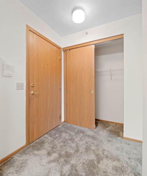 Entryway with two wooden doors and a spacious closet with shelving at Heritage Village in Steubenville, Ohio