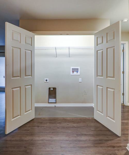 Spacious laundry closet with double doors and shelving, wood-style flooring visible in the background at Oliver Crossing in Linden, Tennessee