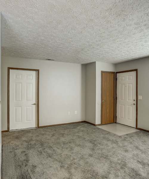 Carpeted living area with dual entry doors at Leewood Place in Fremont, Ohio