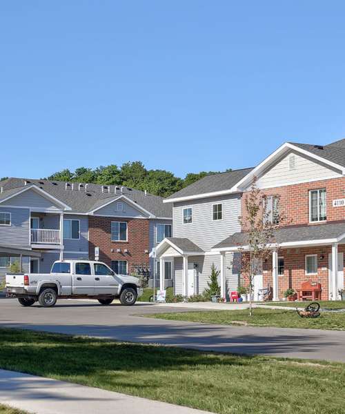 Two-story apartment buildings with landscaped lawns and parked truck in front at Brookside Commons in Traverse City, Michigan