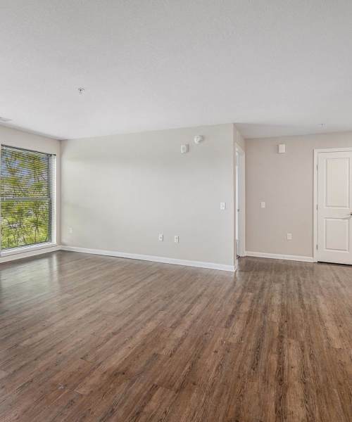 Spacious living area with wood-style flooring and large window providing natural light at Grand View Place in Grand Rapids, Michigan