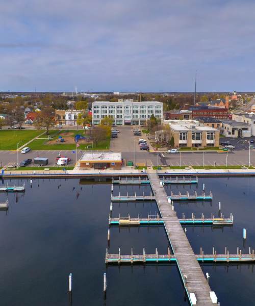 Aerial view of a marina with docks, grassy park, and nearby buildings at Lloyd House I in Menominee, Michigan