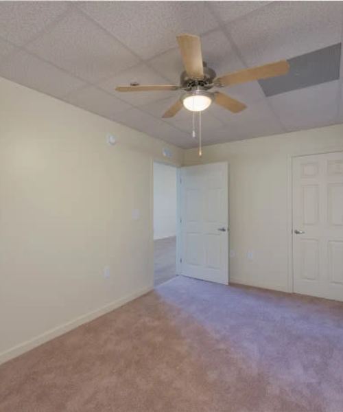 Carpeted bedroom with ceiling fan at A.L. Miller Village in Macon, Georgia