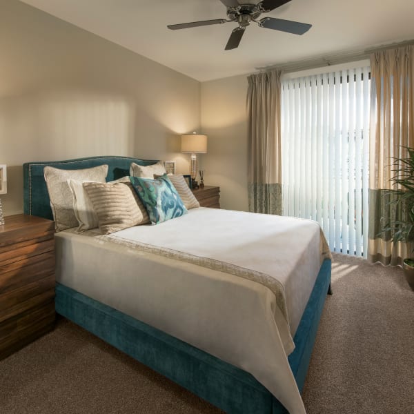 Well-decorated master bedroom with ceiling fan and sliding door to private balcony of model home at San Travesia in Scottsdale, Arizona