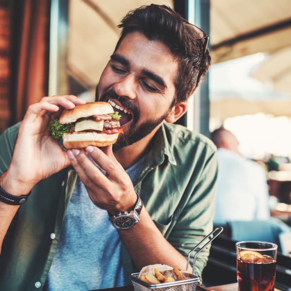 Man eating a delicious sandwich at a restaurant in the neighborhood near The Mayfair Apartment Homes in New Orleans, Louisiana