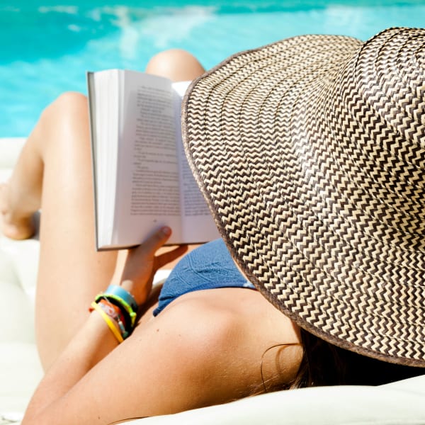 Resident reading a book by the pool at El Potrero Apartments in Bakersfield, California