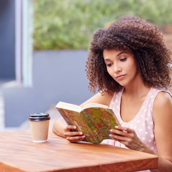 Resident reading a book with her morning coffee at Highland View Court in Bakersfield, California