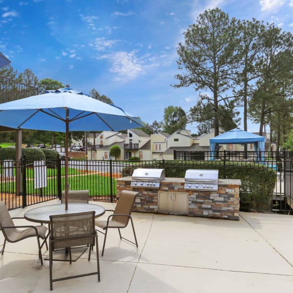 BBQ area next to the pool with seating and umbrellas at the tables at The Flats at Arrowood in Charlotte, North Carolina