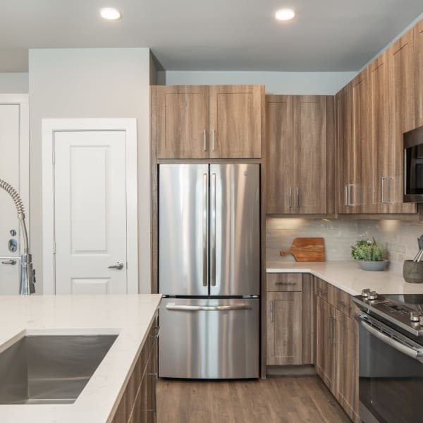 Apartment kitchen with stainless steel fridge and marble countertops at Bellrock Market Station in Katy, Texas