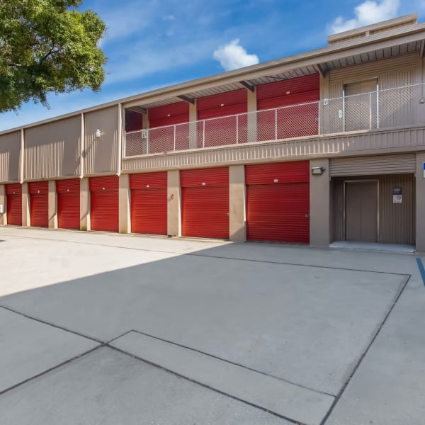 Outdoor drive-up storage units with red doors at StorQuest Self Storage in Tampa, Florida