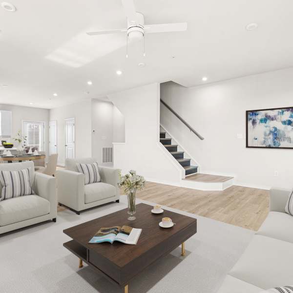 Spacious living room with large area rug and white armchairs at The Westbrook at Brewer's Row in Richmond, Virginia