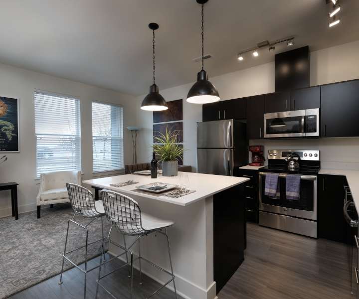 Kitchen island with waterfall faucet, stainless steel appliances and pendant lighting at 27 Elm in Redmond, Oregon
