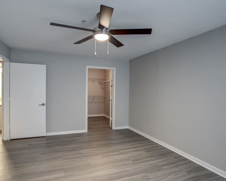 Hardwood floors, walk-in closet, and ceiling fan in bedroom of recently renovated home at Kenwood Club at the Park in Katy, Texas