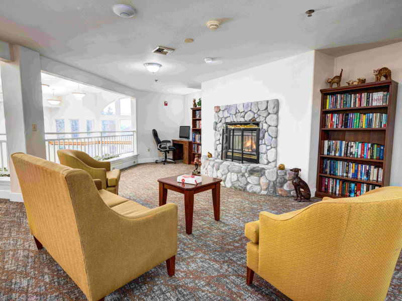 Cozy common room with a fireplace and bookshelf at Callahan Village Retirement  and Assisted Living in Roseburg, Oregon