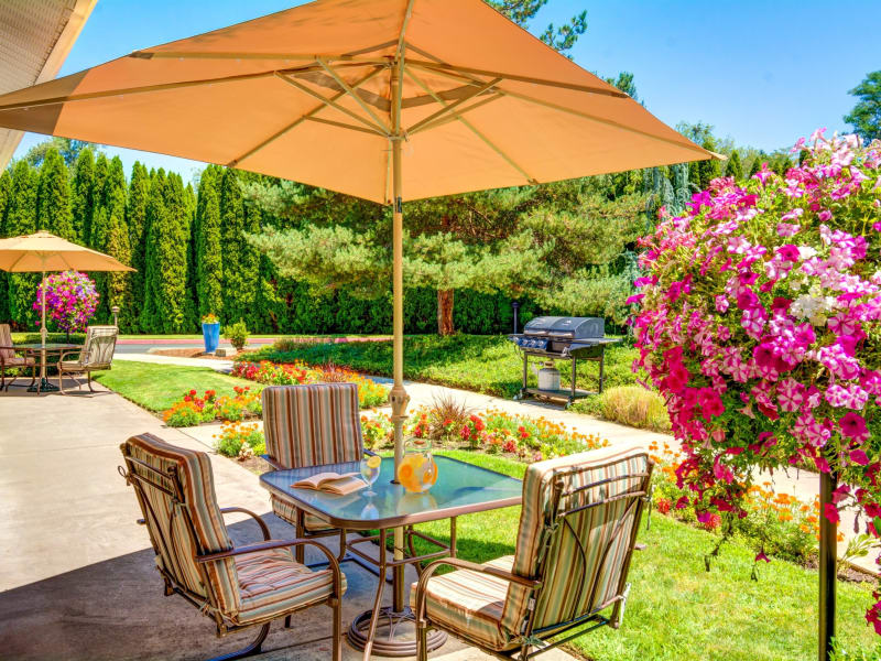 Patio table with an umbrella surrounded by flowers at The Suites Assisted Living and Memory Care in Grants Pass, Oregon