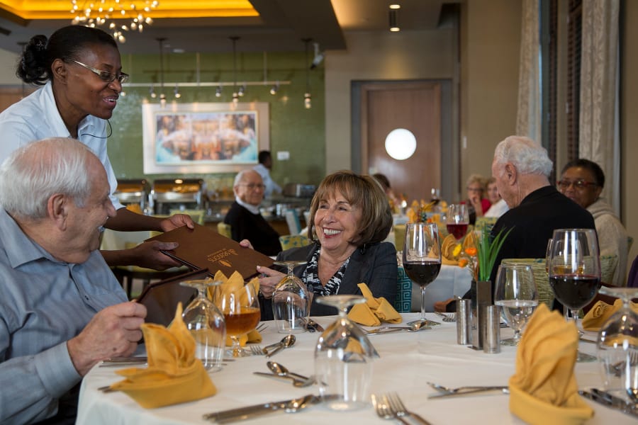 Residents enjoying some wine while placing their restaurant-style meal order at Casa Del Rio Senior Living in Peoria, Arizona
