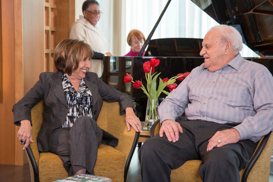 Residents chatting near the grand piano in the lobby at Casa Del Rio Senior Living in Peoria, Arizona