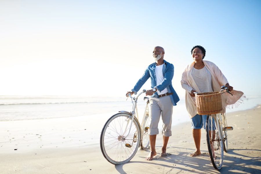 Resident couple walking their bikes on the beach near Carmel Village in Fountain Valley, California