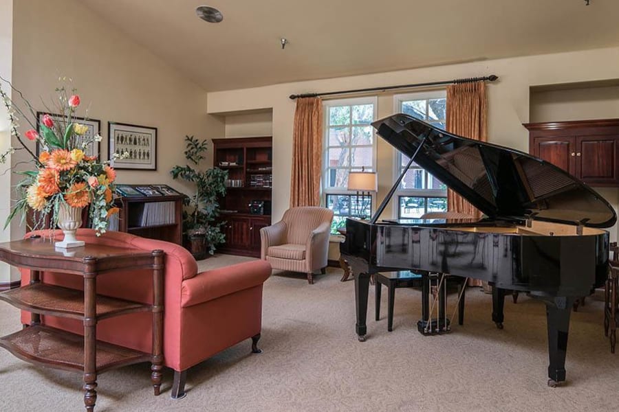 Grand piano with comfortable seating nearby in the lobby at Carmel Village in Fountain Valley, California