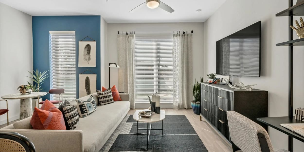 Apartment living room with a blue accent wall at Ross + Peak in Dallas, Texas