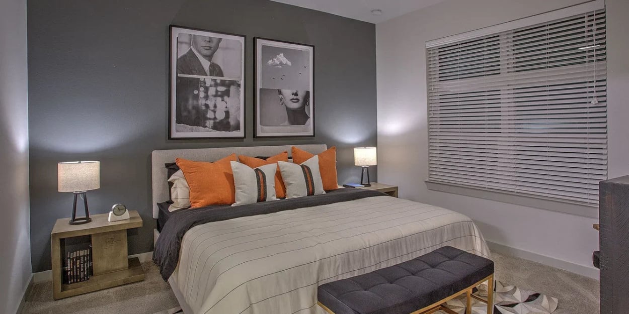 Apartment bedroom with a grey accent wall at Ross + Peak in Dallas, Texas
