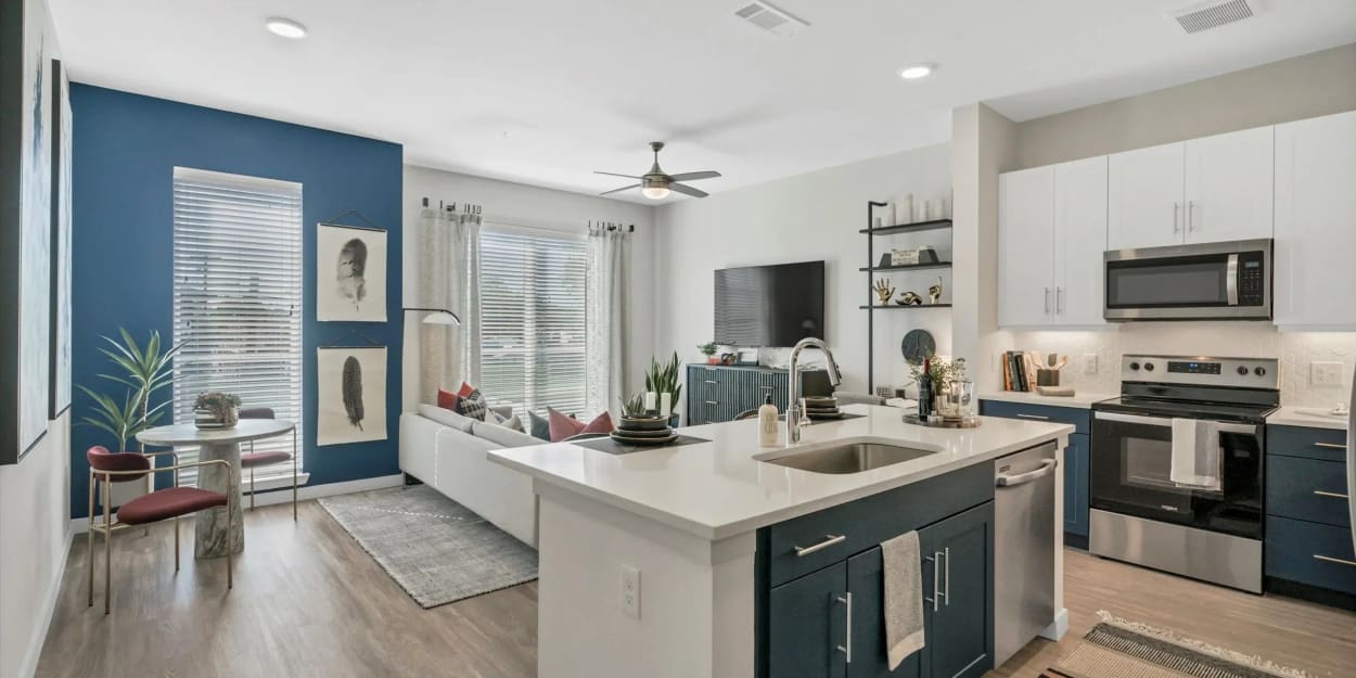 Apartment kitchen and living room with a blue accent wall at Ross + Peak in Dallas, Texas