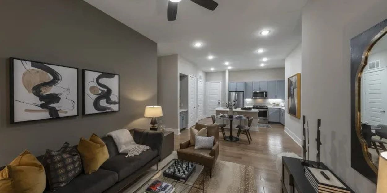 Apartment living room and kitchen with wood-style flooring at The Register in Richardson, Texas